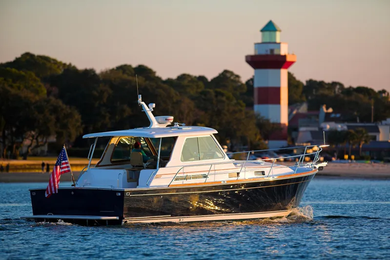 Sparrow Yacht Photos Pics 2004 Sabre 42 Hardtop Express yacht cruising near a lighthouse at sunset.