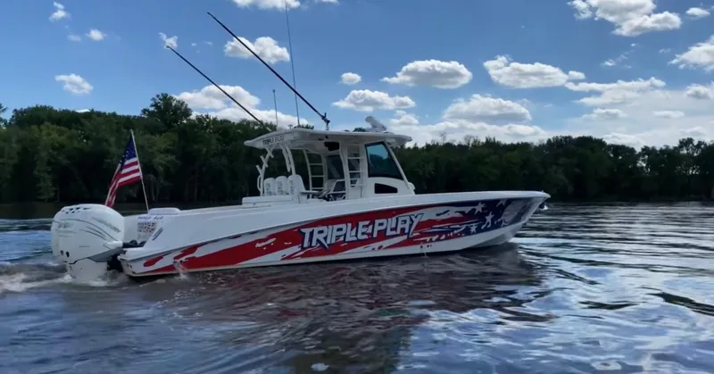 Triple Play Yacht Photos Pics 2015 Boston Whaler 370 Outrage boat on water, American flag, clear sky.