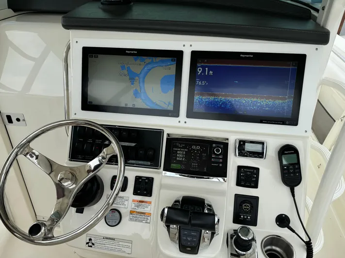 Triple Play Yacht Photos Pics Control panel of a 2015 Boston Whaler 370 Outrage with navigation screens and steering wheel.