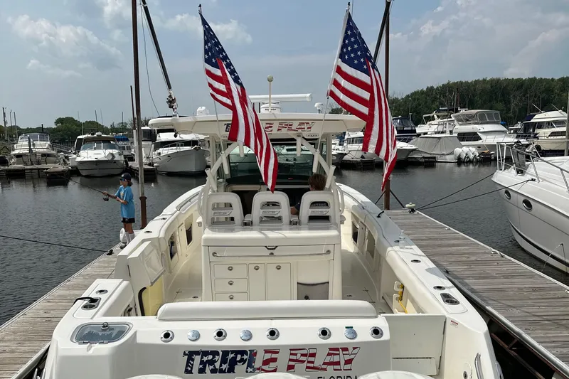 Triple Play Yacht Photos Pics 2015 Boston Whaler 370 Outrage docked, displaying American flags, with marina background.
