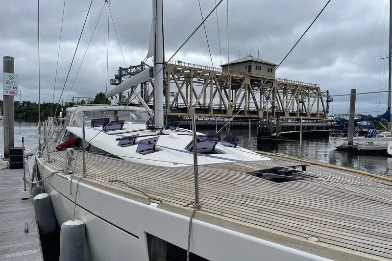Genka Yacht Photos Pics 2017 Beneteau Sense 50 yacht docked near a bridge on a cloudy day.