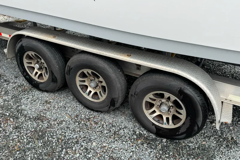  Yacht Photos Pics Triple-axle trailer for 2021 Sportsman Open 322 Center Console on gravel surface.