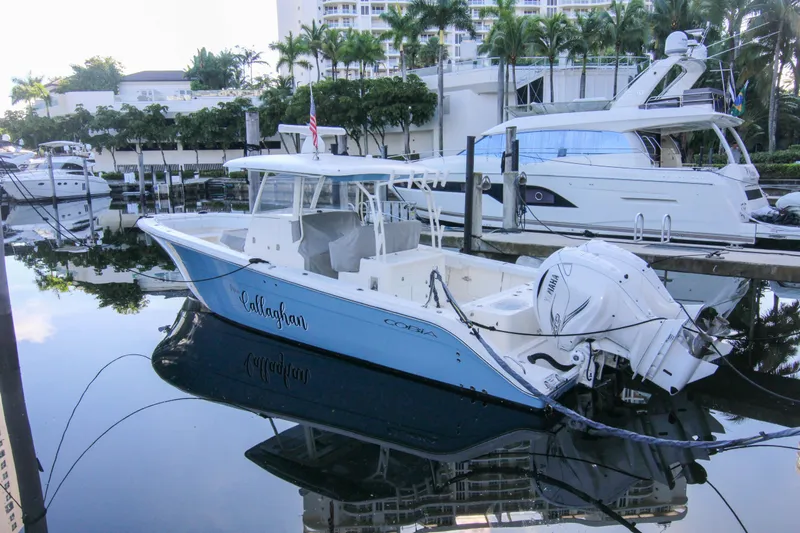  Yacht Photos Pics 2022 Cobia 350 Center Console boat docked in marina, surrounded by yachts and palm trees.