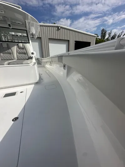  Yacht Photos Pics 2024 Onslow Bay 41 boat deck with seating, near a metal building under a cloudy sky.