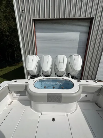  Yacht Photos Pics 2024 Onslow Bay 41 boat with four powerful outboard engines, docked near a metal building.