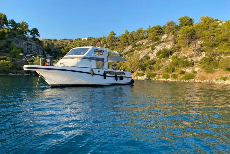 Captain Back Yacht Photos Pics 1988 Cantiere Navale di Pesaro Studio Mare Atmosfere 46 yacht on serene water, surrounded by lush greenery.