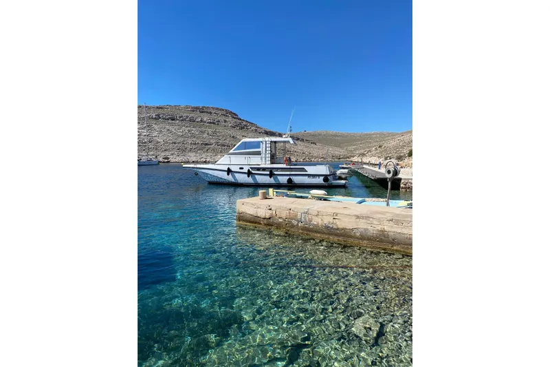 Captain Back Yacht Photos Pics 1988 Cantiere Navale di Pesaro Studio Mare Atmosfere 46 yacht docked in clear blue waters.