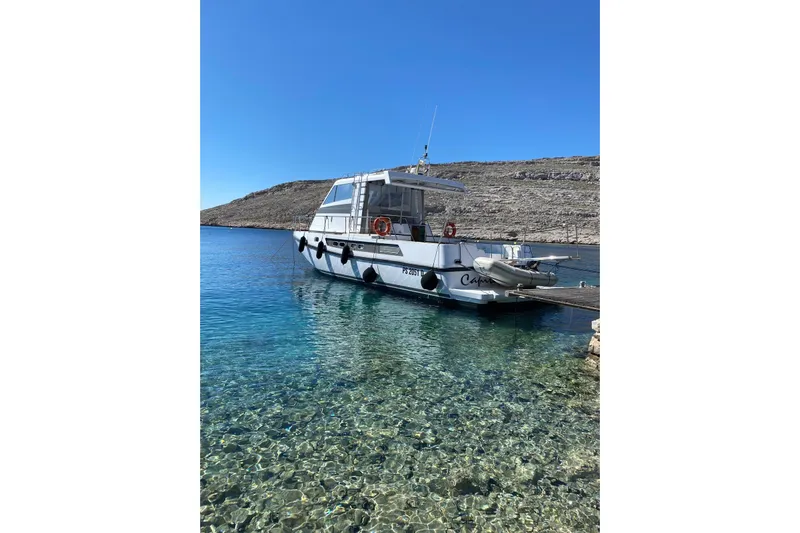 Captain Back Yacht Photos Pics 1988 Cantiere Navale di Pesaro Studio Mare Atmosfere 46 yacht docked in clear blue water.