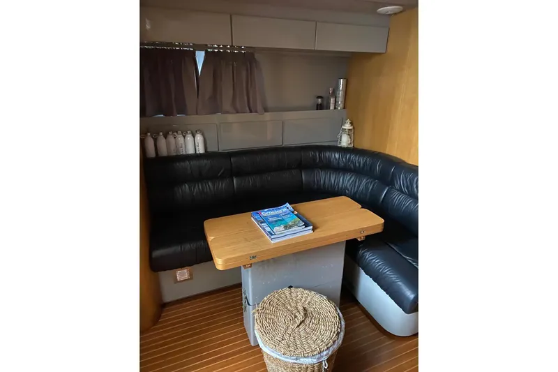 Captain Back Yacht Photos Pics Cozy interior of 1988 Studio Mare Atmosfere 46 yacht with leather seating and wooden table.