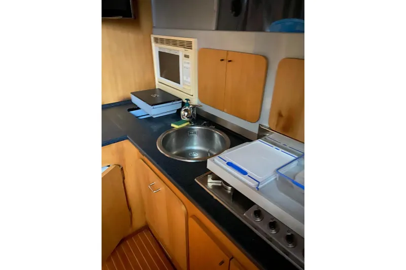 Captain Back Yacht Photos Pics Compact yacht kitchen with sink, microwave, and stove in 1988 Studio Mare Atmosfere 46.