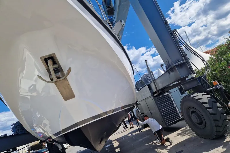 Captain Back Yacht Photos Pics Studio Mare Atmosfere 46 yacht being lifted by crane, 1988 model, under clear blue sky.
