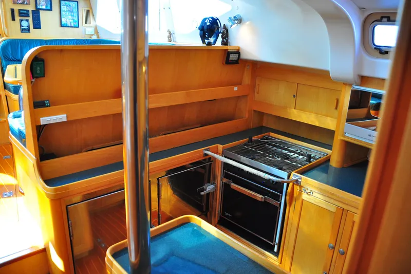 Raynad Yacht Photos Pics Interior of 2000 Custom Steel Cutter World Cruiser yacht kitchen with wooden cabinetry and stove.