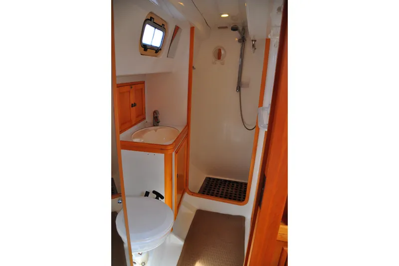 Raynad Yacht Photos Pics Compact bathroom in 2000 Custom Steel Cutter World Cruiser yacht, featuring shower, sink, and toilet.