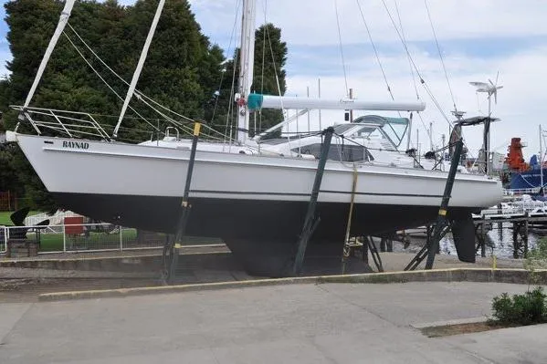 Raynad Yacht Photos Pics Custom Steel Cutter World Cruiser 2000 sailboat on dry dock, marina background.