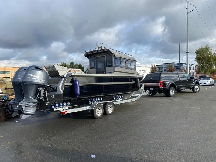  Yacht Photos Pics 2022 Custom Aluminum Fishing boat on trailer, attached to a black truck, under cloudy skies.