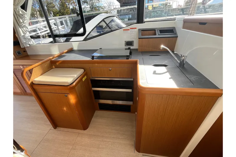  Yacht Photos Pics 2019 Beneteau Swift Trawler 35 interior kitchen with wood cabinetry and modern appliances.