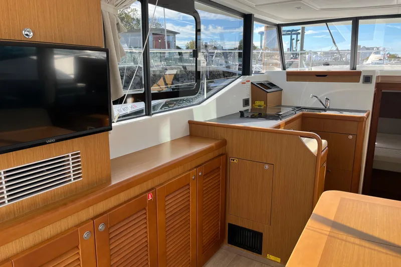  Yacht Photos Pics 2019 Beneteau Swift Trawler 35 interior with kitchen and TV, featuring wood cabinetry.