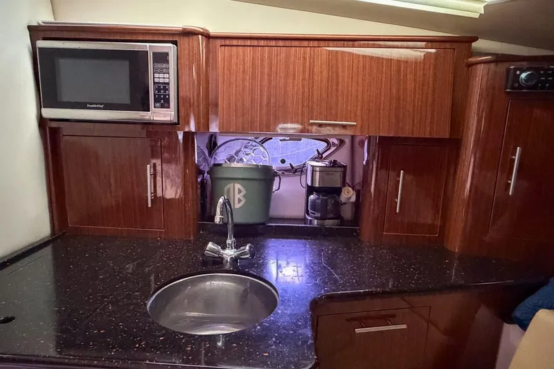 Sophia Yacht Photos Pics 2015 Regal 38 Express yacht kitchen with microwave, sink, and wooden cabinets.