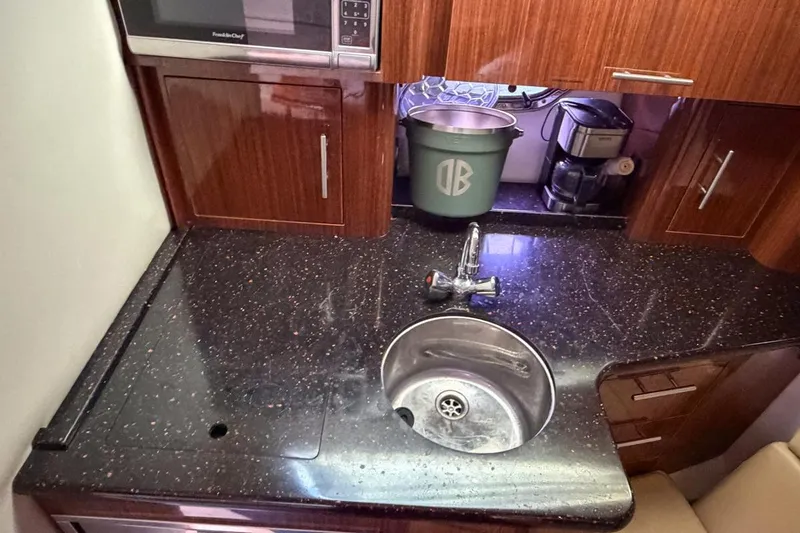 Sophia Yacht Photos Pics 2015 Regal 38 Express yacht kitchen with sink, microwave, and wooden cabinetry.