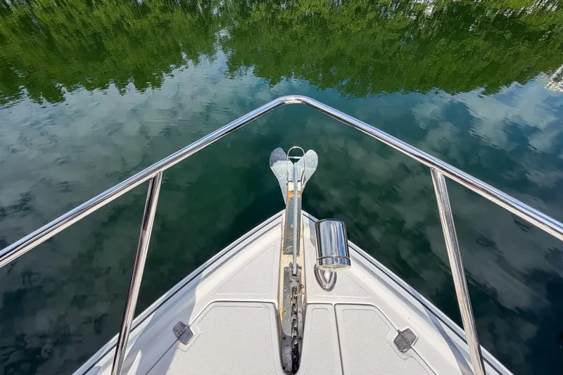 Sophia Yacht Photos Pics Bow view of 2015 Regal 38 Express boat on calm water reflecting trees.