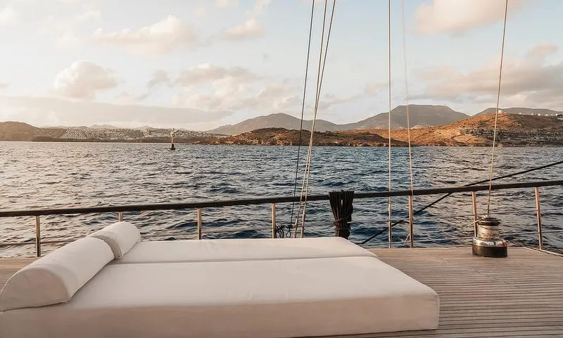 27 M Deluxe Gulet Yacht Photos Pics Custom 2003 motorsailor deck with sunbed, overlooking serene ocean and distant hills.