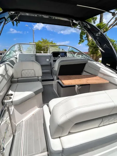 Yacht Photos Pics 2023 Regal 26 XO boat interior with luxurious seating and wooden table under a clear blue sky.
