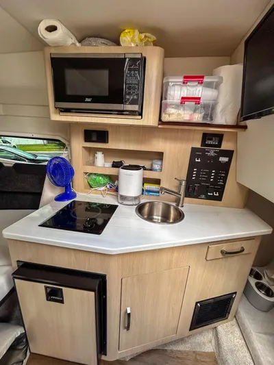  Yacht Photos Pics Compact kitchen area in 2023 Regal 26 XO boat with microwave, sink, and storage.