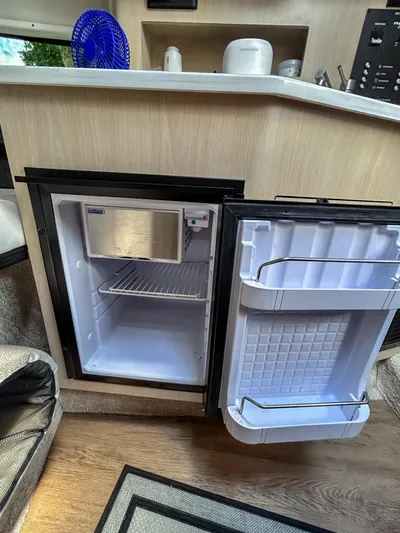  Yacht Photos Pics 2023 Regal 26 XO boat interior with open mini fridge, wooden cabinetry, and countertop.