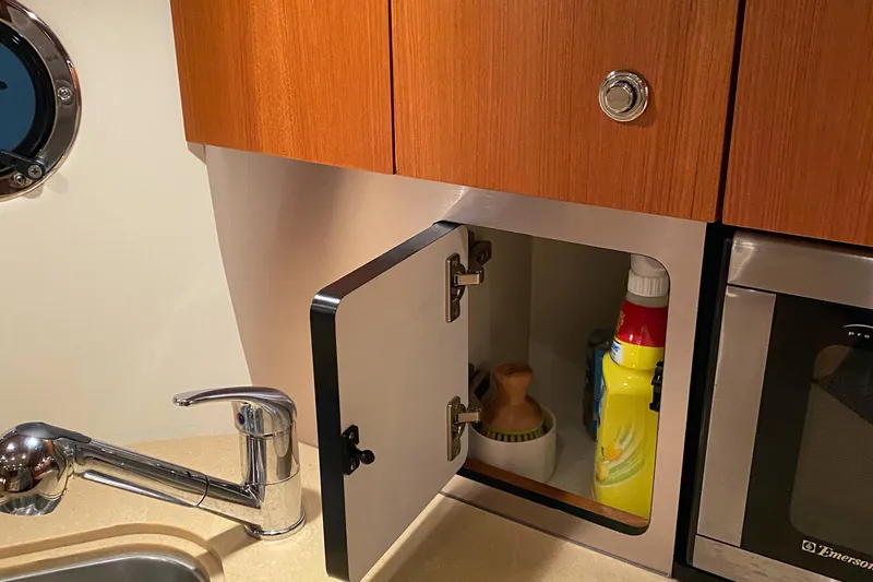  Yacht Photos Pics 2005 Tiara Yachts 3600 Sovran kitchen cabinet with open door, faucet, and cleaning supplies.