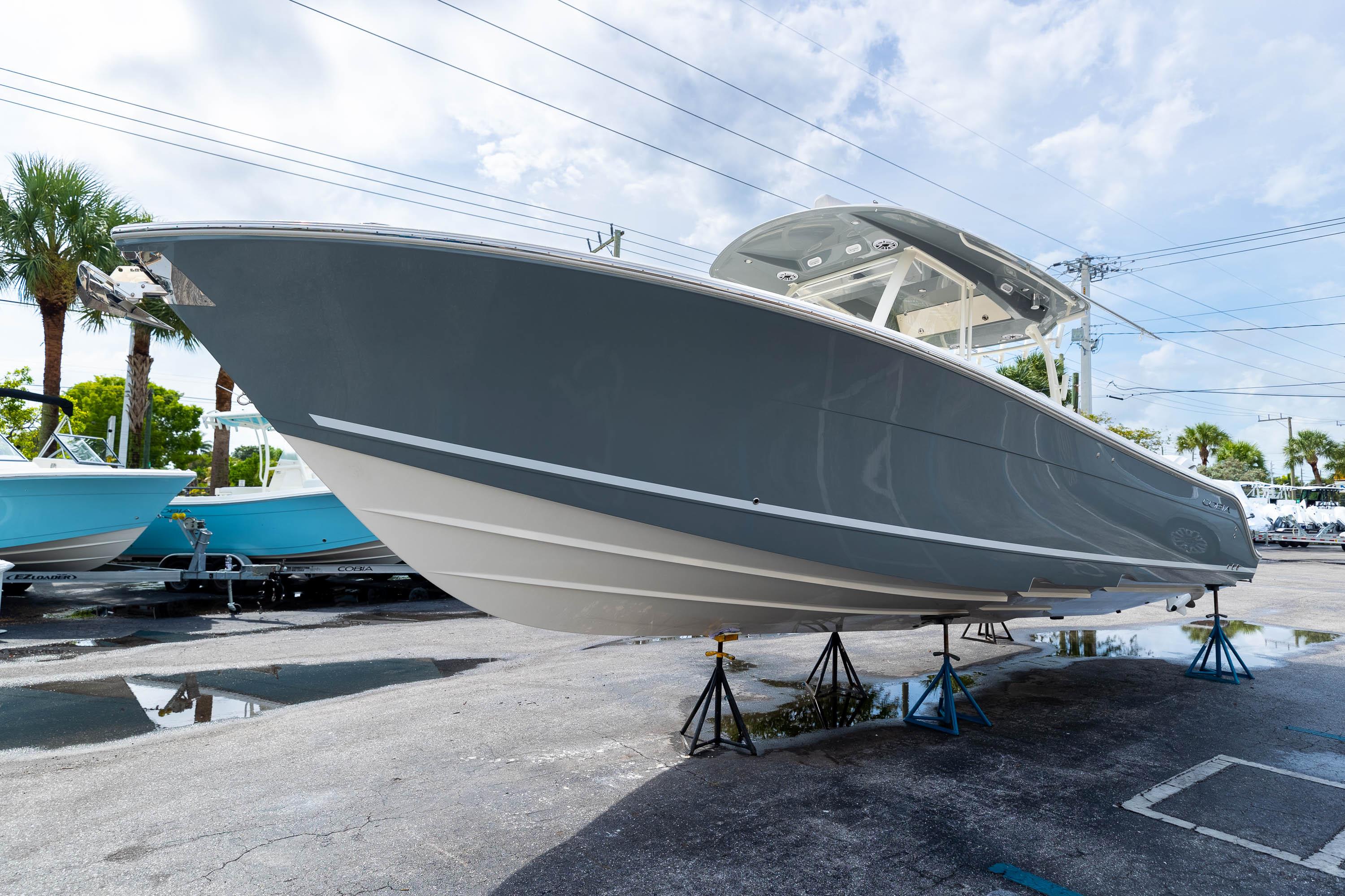 2023 Cobia 350 Center Console boat on display, elevated on stands, under a cloudy sky.