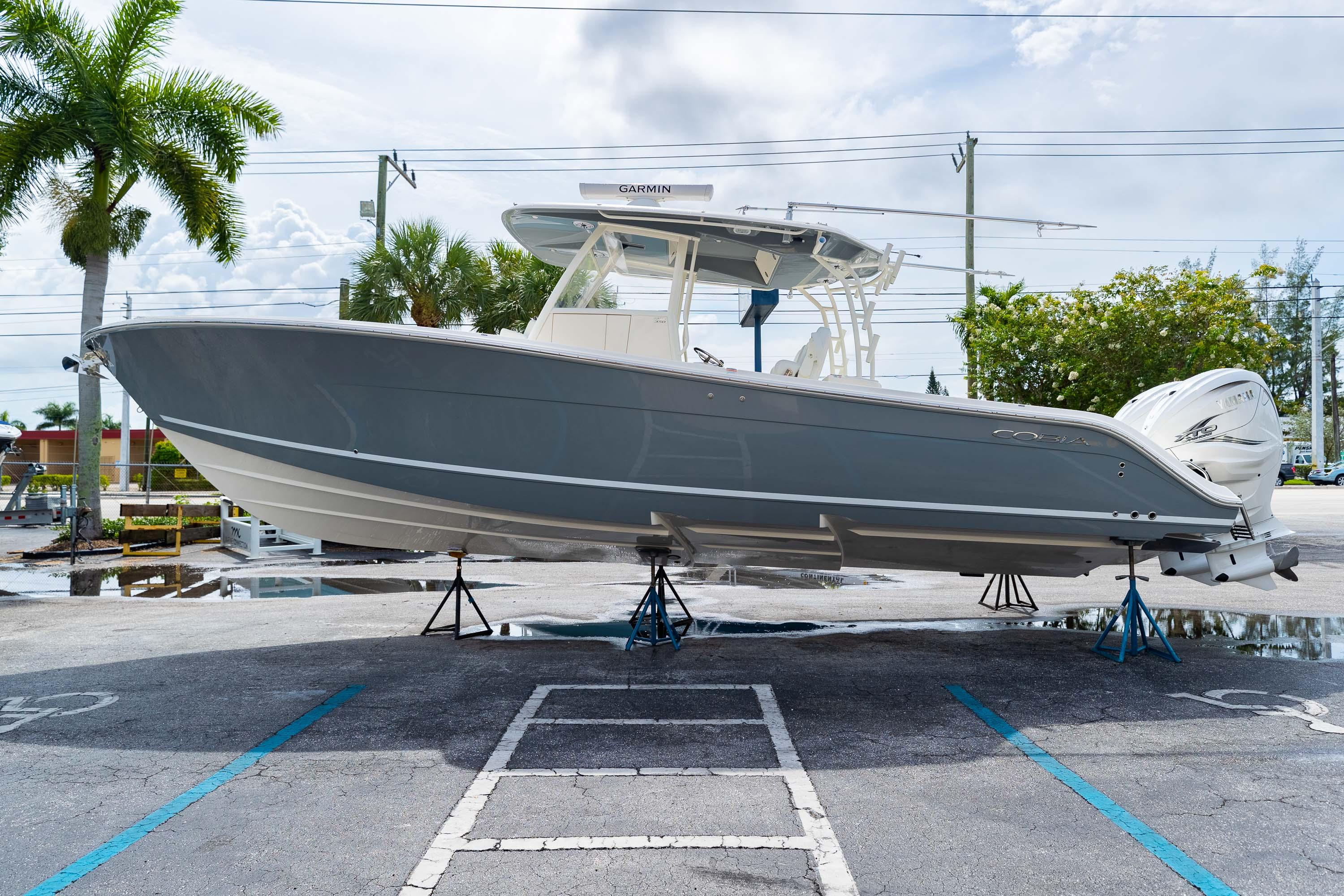 2023 Cobia 350 Center Console boat displayed on stands in a parking lot.