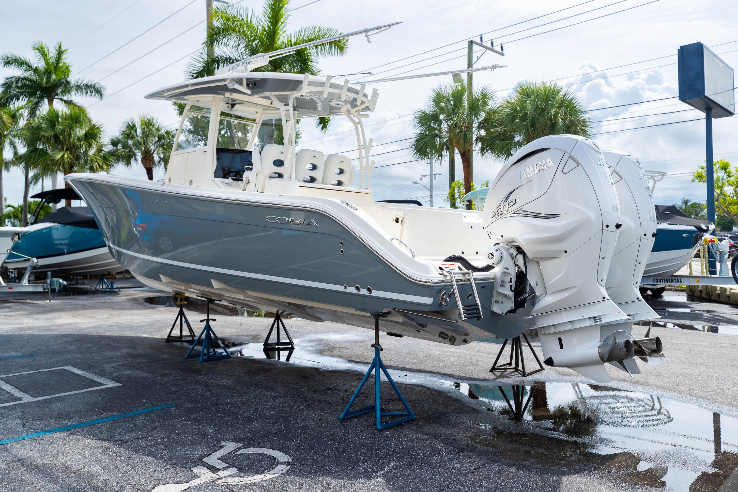 2023 Cobia 350 Center Console boat on display, elevated on stands, with palm trees in background.