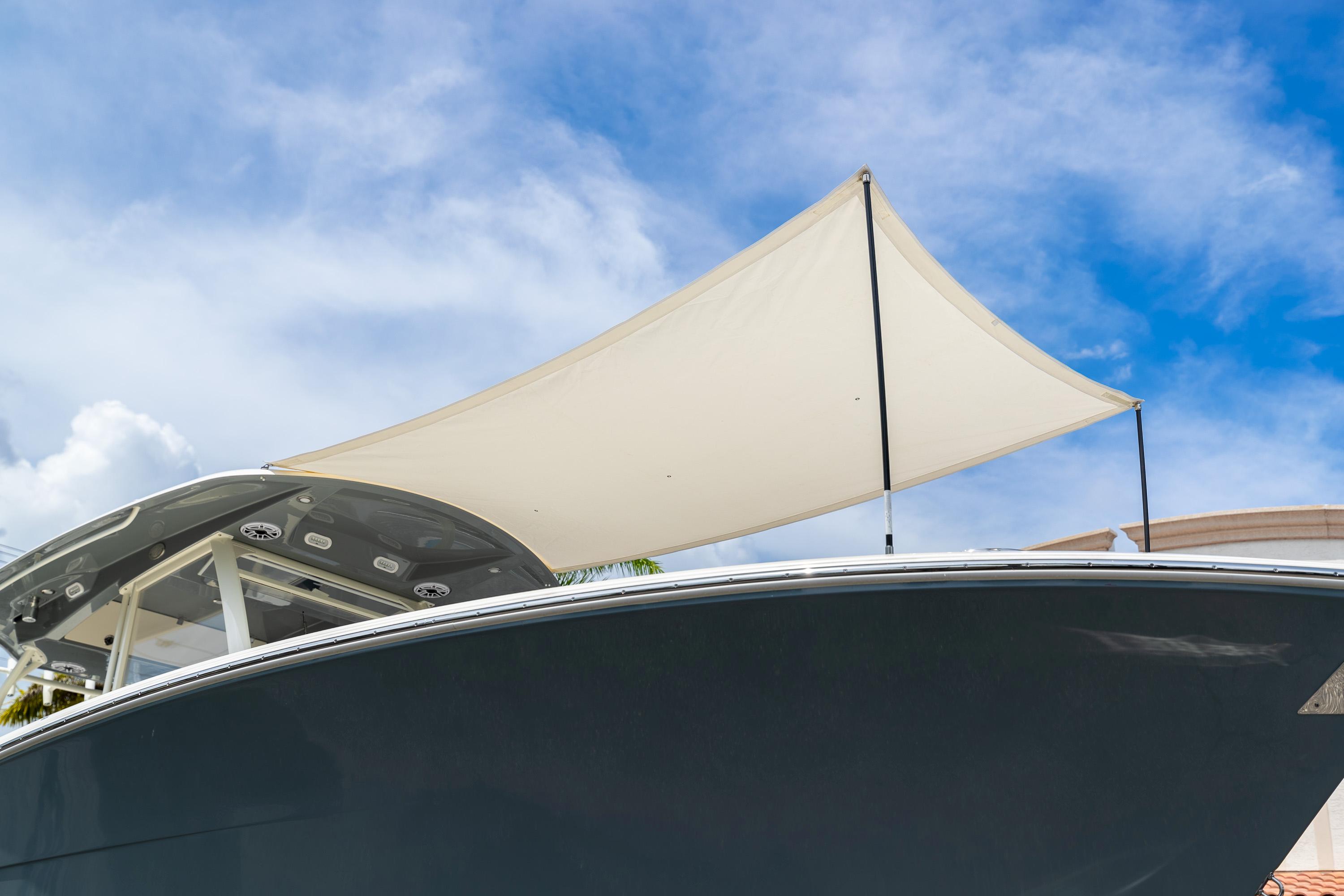 2023 Cobia 350 Center Console boat with canopy against blue sky.