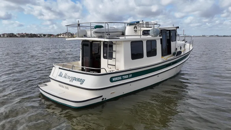 Ms. Moneypenny Yacht Photos Pics 2001 Nordic Tug 37 boat on calm water under a cloudy sky.