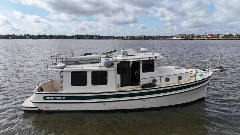 Ms. Moneypenny Yacht Photos Pics 2001 Nordic Tug 37 boat on calm water under a cloudy sky.