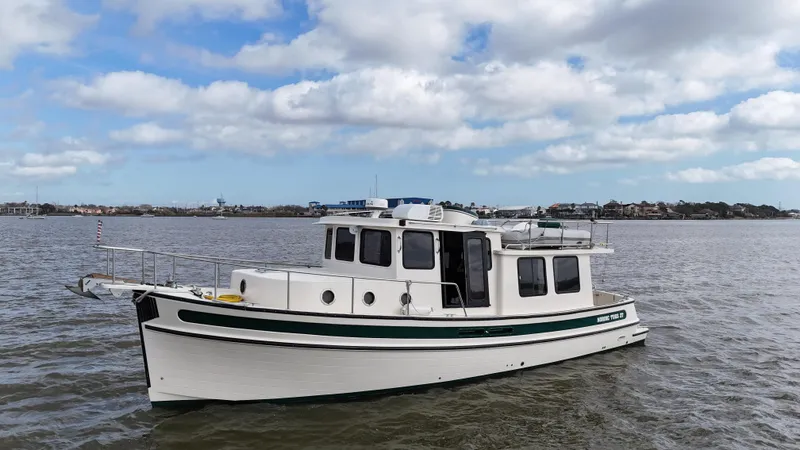 Ms. Moneypenny Yacht Photos Pics 2001 Nordic Tug 37 cruising on calm waters under a partly cloudy sky.