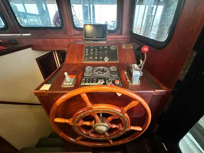 Ms. Moneypenny Yacht Photos Pics Pilothouse of 2001 Nordic Tug 37 with wooden wheel and control panel.