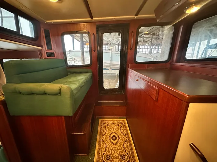 Ms. Moneypenny Yacht Photos Pics Interior of 2001 Nordic Tug 37 with green seating and wooden cabinetry.