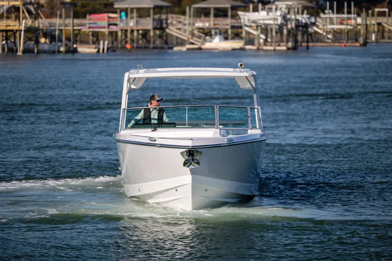  Yacht Photos Pics 2023 Aviara AV32 OB boat cruising on a calm waterway near docks.