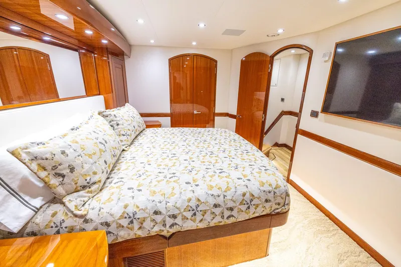  Yacht Photos Pics Luxurious bedroom interior of 2024 Hatteras GT70 yacht with elegant wood finishes.