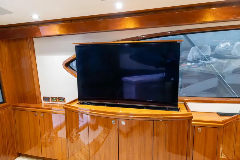  Yacht Photos Pics Luxurious interior of 2024 Hatteras GT70 yacht with sleek wooden cabinetry and large TV.