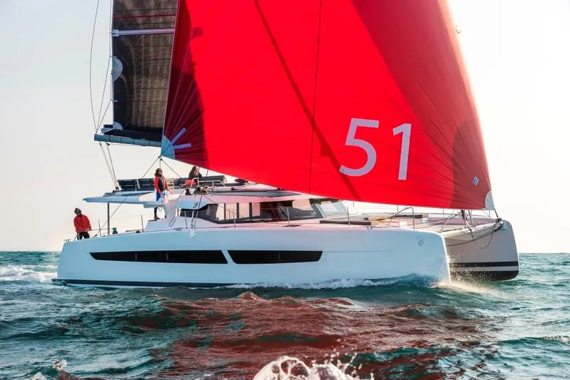  Yacht Photos Pics 2025 Fountaine Pajot Catamaran Aura 51 sailing with vibrant red sails on open water.