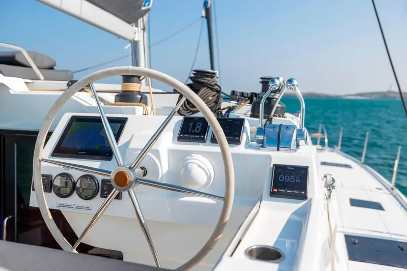  Yacht Photos Pics 2025 Fountaine Pajot Catamaran Aura 51 helm with modern navigation instruments, sailing on open sea.