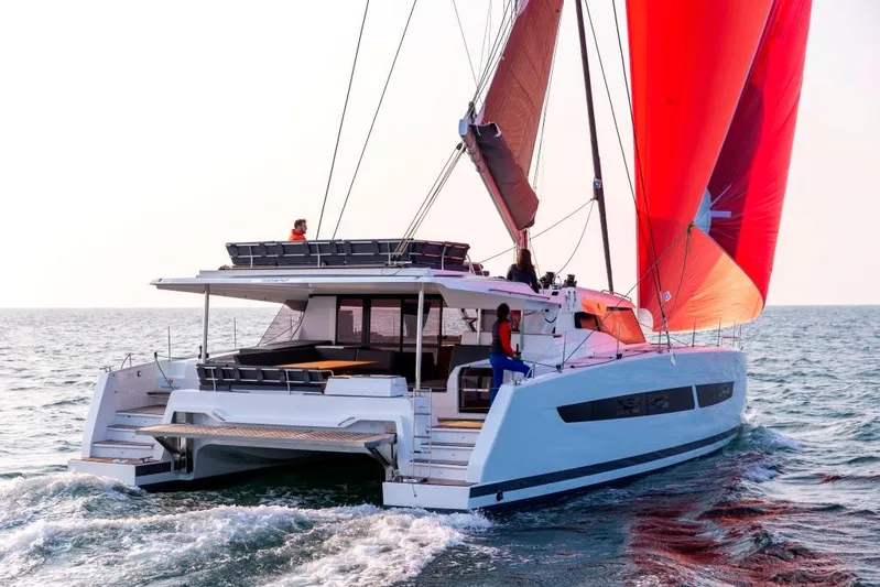  Yacht Photos Pics 2025 Fountaine Pajot Catamaran Aura 51 sailing with vibrant red sails on open water.