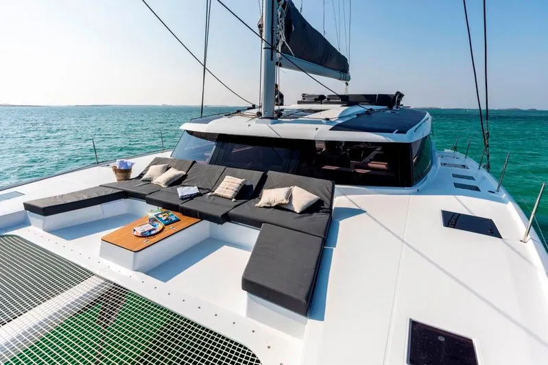  Yacht Photos Pics 2025 Fountaine Pajot Catamaran Aura 51 on tranquil sea, featuring luxurious deck seating.