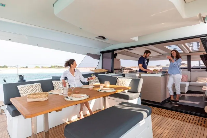  Yacht Photos Pics 2025 Fountaine Pajot Catamaran Aura 51 interior with people dining and relaxing.