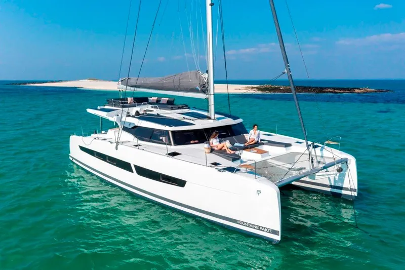  Yacht Photos Pics 2025 Fountaine Pajot Catamaran Aura 51 sailing in turquoise waters near a sandy island.