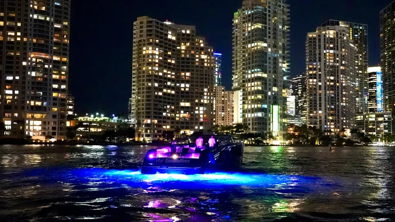 The Godfather Yacht Photos Pics VanDutch 55 yacht illuminated on water at night, city skyline in background.