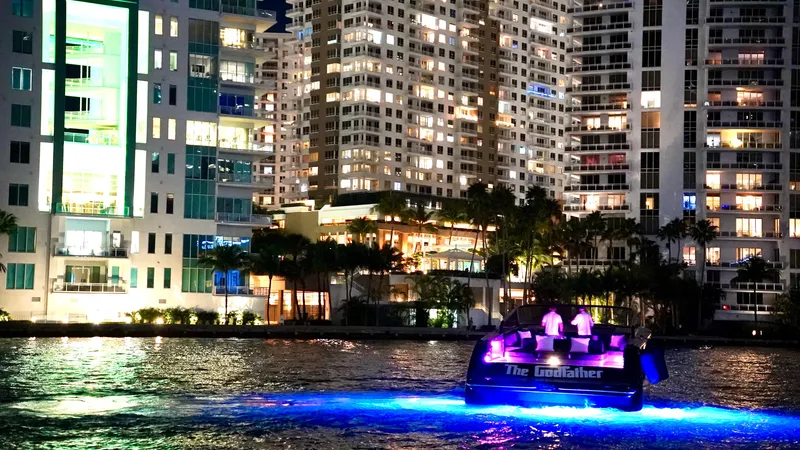 The Godfather Yacht Photos Pics VanDutch 55 yacht illuminated on water at night, city skyline in background.