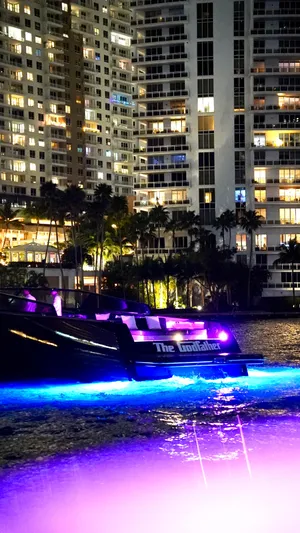 The Godfather Yacht Photos Pics VanDutch 55 yacht with vibrant lights against city skyline at night, 2014 model.